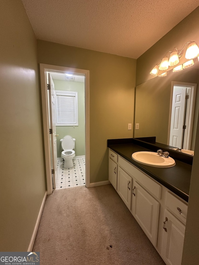 bathroom with vanity, baseboards, a textured ceiling, and toilet
