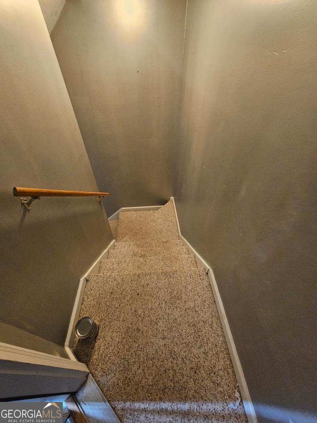 staircase featuring baseboards and carpet flooring
