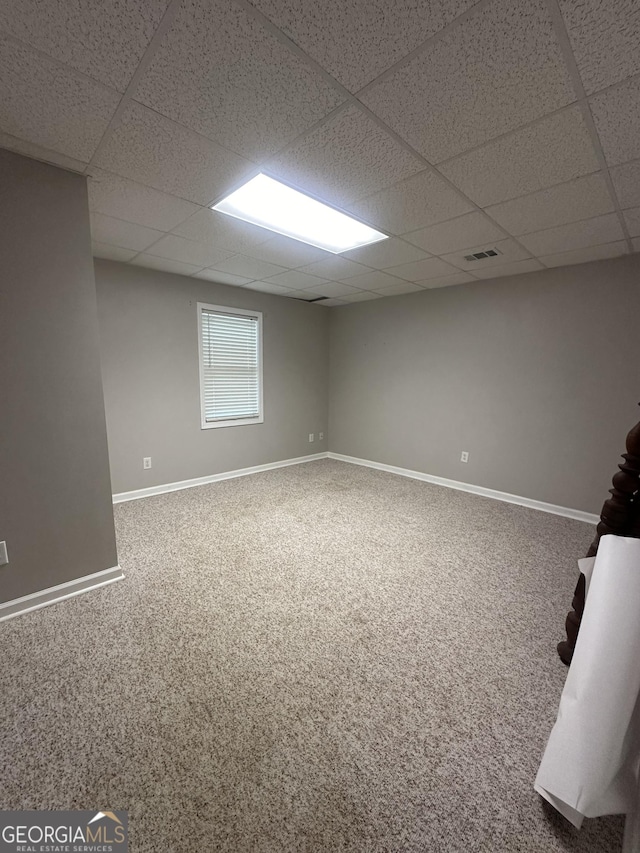 below grade area with a drop ceiling, carpet floors, and baseboards