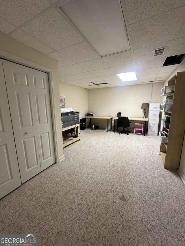 carpeted home office with a paneled ceiling