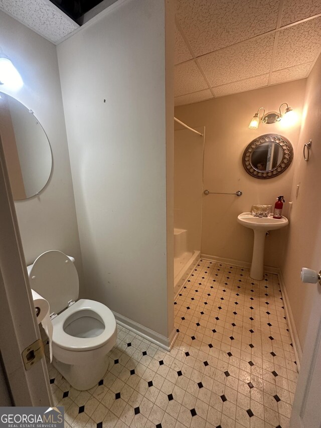 full bath with a shower, baseboards, toilet, and a paneled ceiling