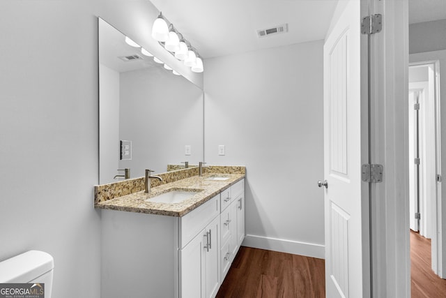 bathroom featuring visible vents, wood finished floors, a sink, and toilet