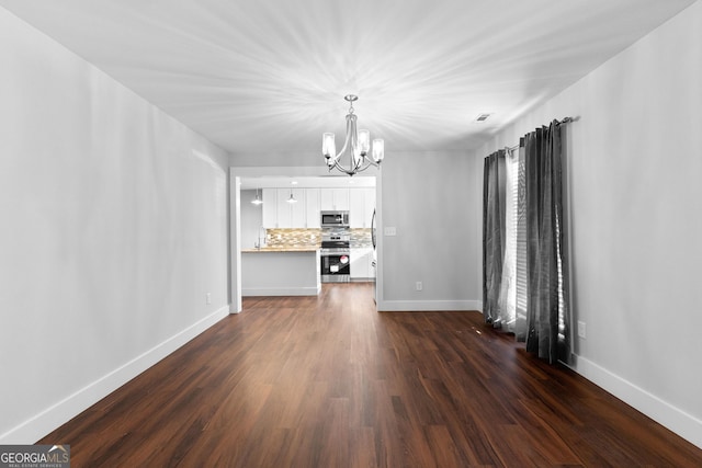 unfurnished living room with an inviting chandelier, dark wood-type flooring, visible vents, and baseboards