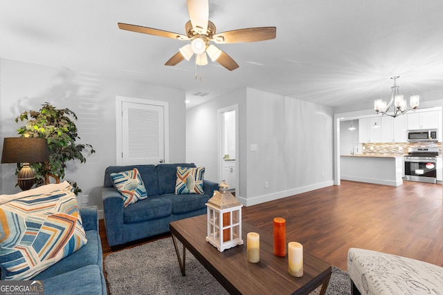living room featuring wood finished floors, visible vents, baseboards, and ceiling fan with notable chandelier