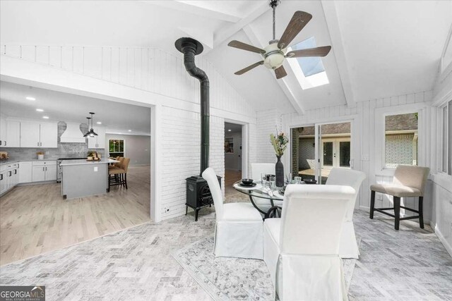7300 Wynhill Dr, Sandy Springs, GA 30328 - dining area featuring high vaulted ceiling, ceiling fan, a wood stove, beamed ceiling, and light wood-style flooring