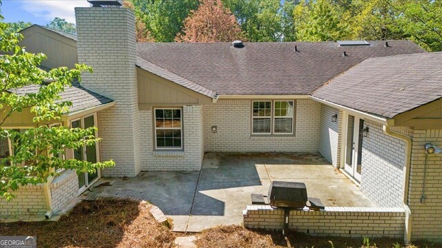 7300 Wynhill Dr, Sandy Springs, GA 30328 - back of property with a patio area, a chimney, roof with shingles, and brick siding