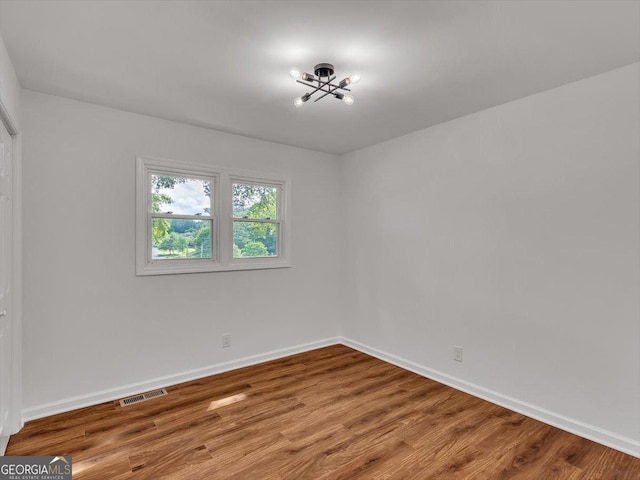 110 Dorsey St, Calhoun, GA 30701 - empty room with wood finished floors, visible vents, baseboards, and a notable chandelier