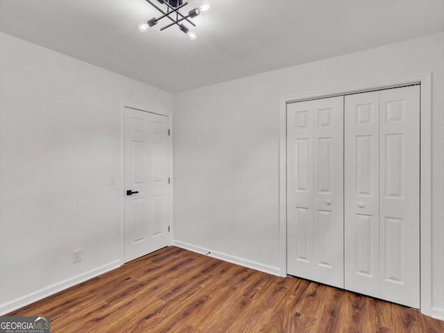 110 Dorsey St, Calhoun, GA 30701 - unfurnished bedroom featuring baseboards, a closet, an inviting chandelier, and wood finished floors
