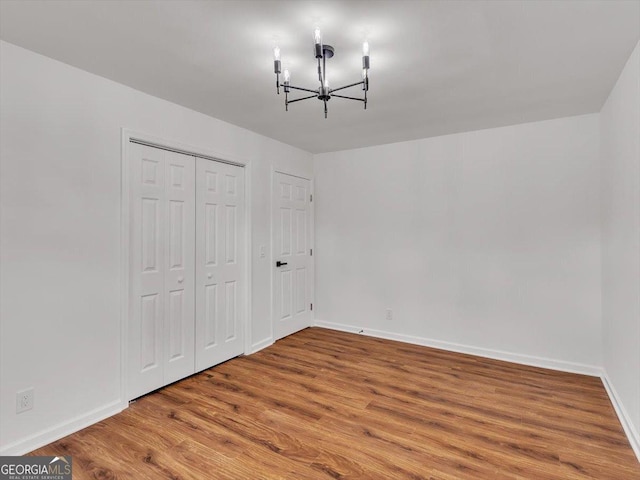 110 Dorsey St, Calhoun, GA 30701 - unfurnished bedroom featuring baseboards, a closet, an inviting chandelier, and wood finished floors