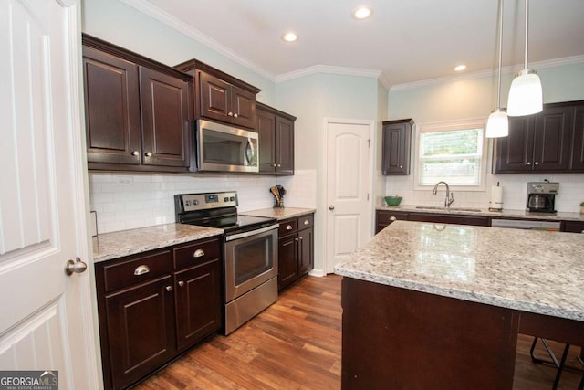 kitchen featuring dark wood finished floors, stainless steel appliances, a sink, dark brown cabinetry, and decorative backsplash
