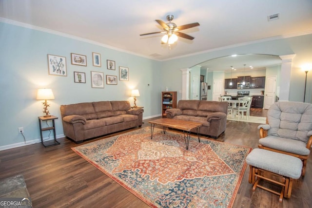 living area with decorative columns, arched walkways, dark wood-type flooring, and a ceiling fan