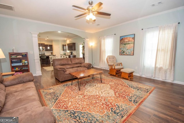 living room featuring arched walkways, visible vents, a ceiling fan, and ornate columns