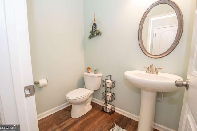 bathroom with toilet, wood finished floors, and baseboards