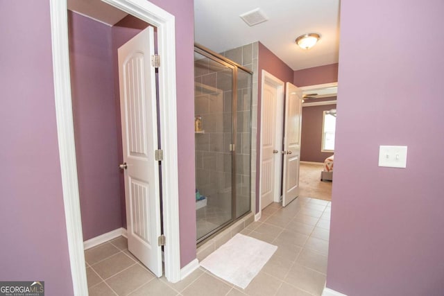 bathroom featuring tile patterned flooring, visible vents, baseboards, a stall shower, and ensuite bathroom