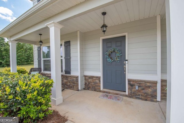 entrance to property featuring a porch and stone siding