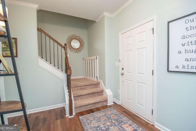 entryway featuring baseboards, wood finished floors, crown molding, and stairs
