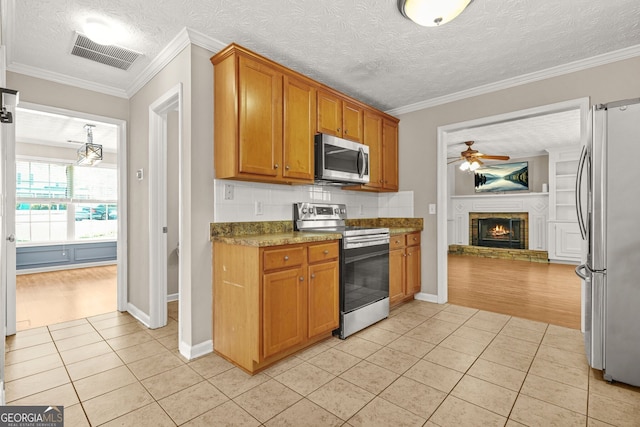 kitchen featuring ceiling fan, appliances with stainless steel finishes, dark countertops, light tile patterned floors, and visible vents