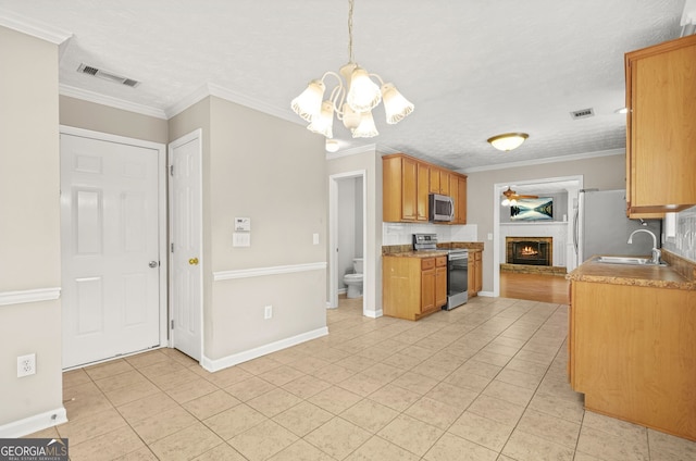 kitchen with light tile patterned flooring, a notable chandelier, a sink, a brick fireplace, and stainless steel appliances