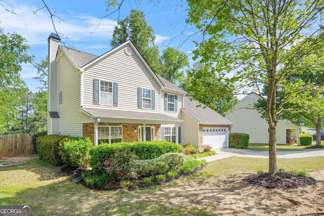 traditional-style home with a chimney, fence, concrete driveway, an attached garage, and stone siding