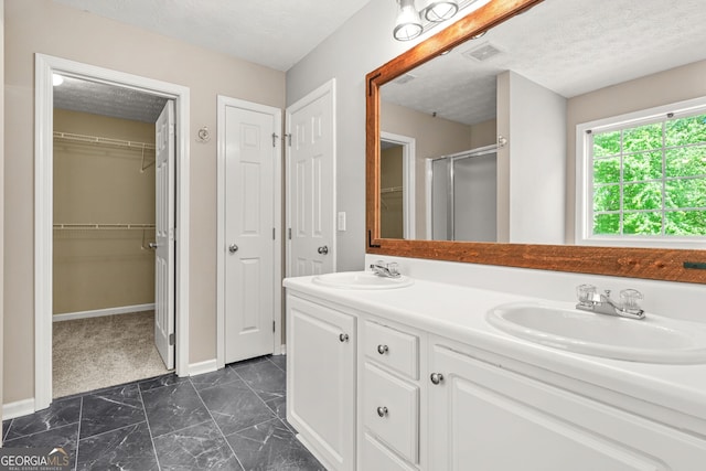 full bath with visible vents, marble finish floor, a textured ceiling, a sink, and a stall shower
