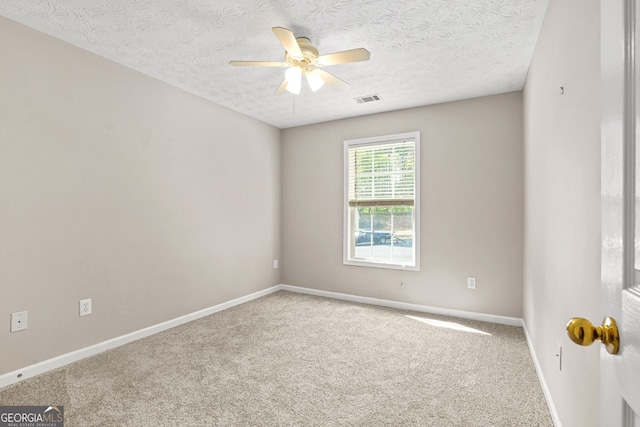 empty room with carpet flooring, a textured ceiling, ceiling fan, and visible vents