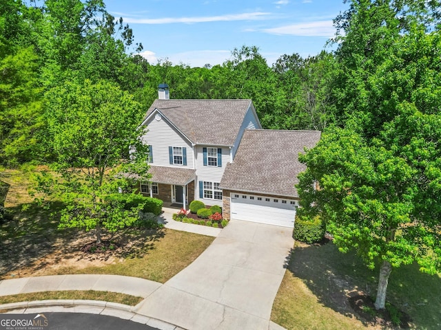 traditional-style home featuring a garage, roof with shingles, driveway, and a chimney