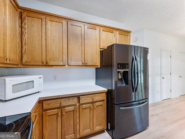kitchen with stainless steel fridge, white microwave, electric range oven, and light countertops