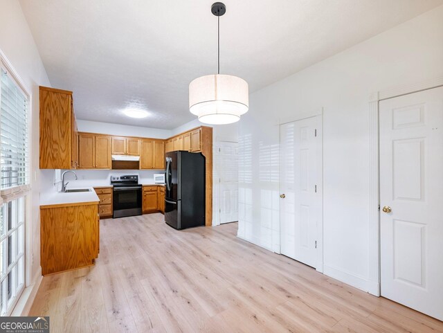 kitchen with black appliances, a sink, light wood-style flooring, and light countertops