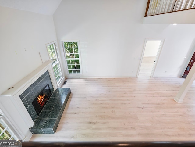 unfurnished living room featuring high vaulted ceiling, a premium fireplace, wood finished floors, and baseboards
