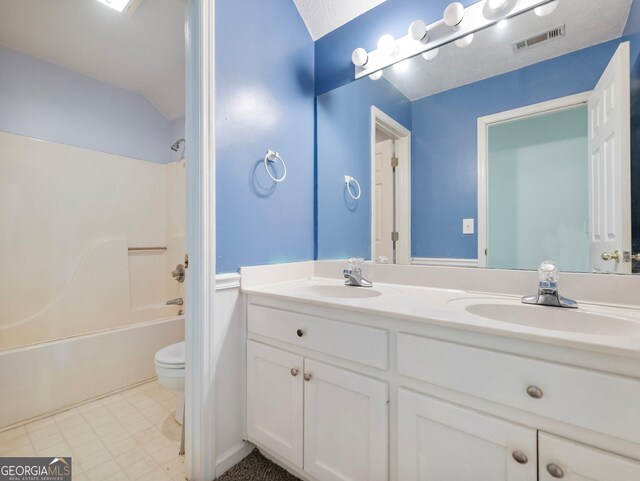 bathroom featuring toilet, double vanity, and shower / bathtub combination
