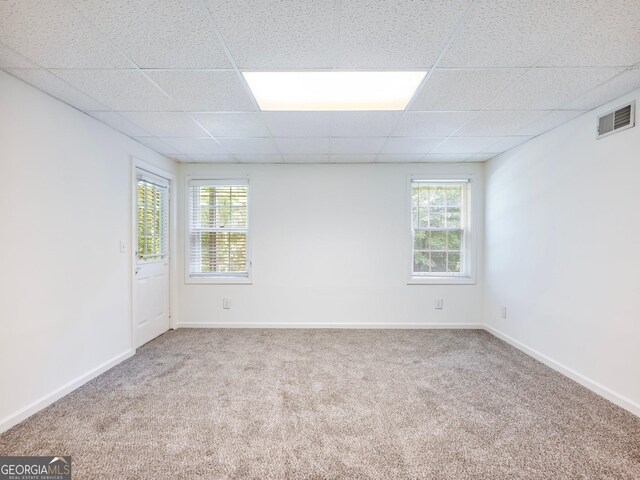 spare room featuring carpet flooring, a drop ceiling, plenty of natural light, and baseboards