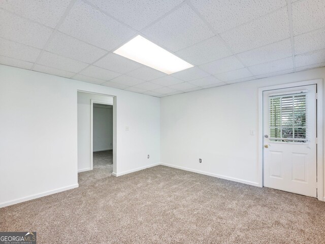 carpeted empty room with a paneled ceiling and baseboards