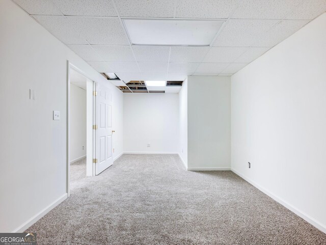 finished basement featuring carpet flooring, a paneled ceiling, and baseboards