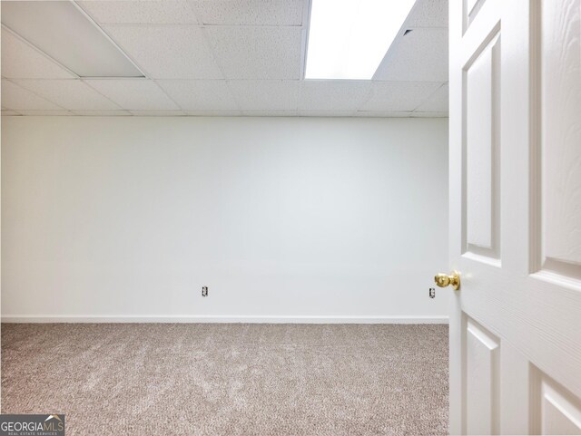 unfurnished room featuring carpet, a paneled ceiling, and baseboards