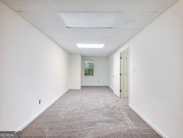 carpeted spare room featuring a paneled ceiling and baseboards
