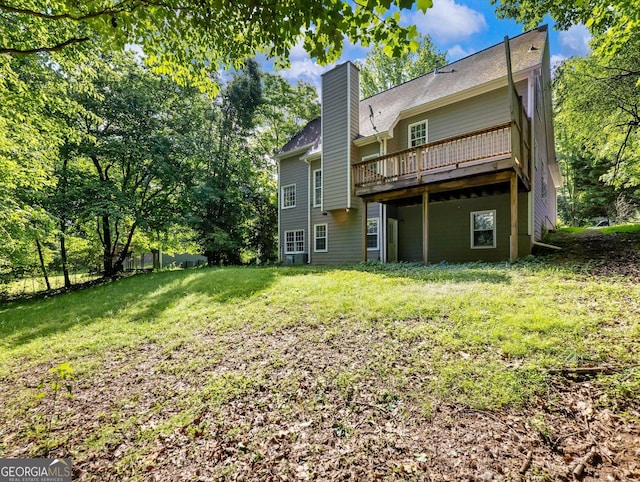 rear view of house with a chimney, a deck, and a lawn