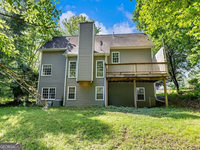 rear view of house featuring a chimney, a deck, and a yard