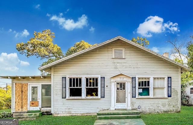 bungalow-style home featuring a chimney and a front lawn