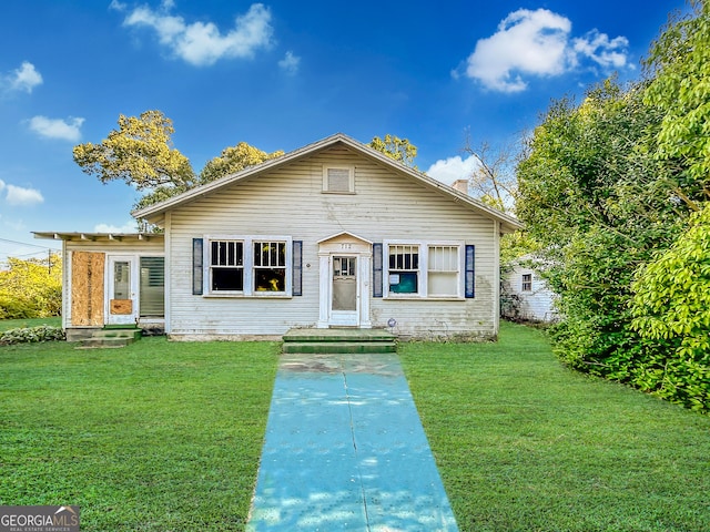 bungalow featuring a front lawn and a chimney