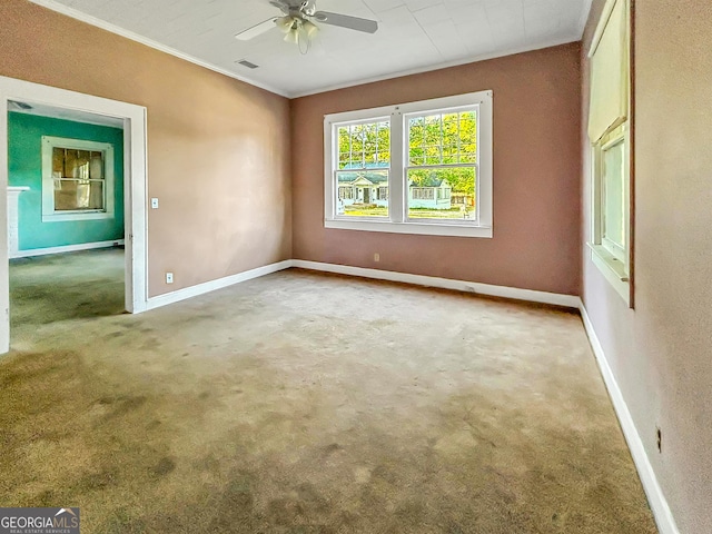 carpeted spare room featuring baseboards, a ceiling fan, visible vents, and ornamental molding