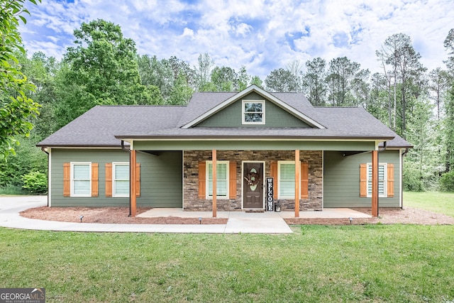 view of front facade with a front yard, stone siding, and roof with shingles