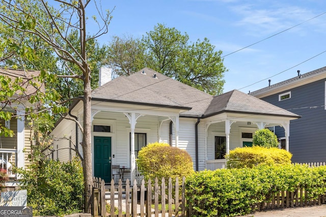 69 Hogue St NE, Atlanta, GA 30312 - shotgun-style home featuring a porch, a fenced front yard, a chimney, and a shingled roof