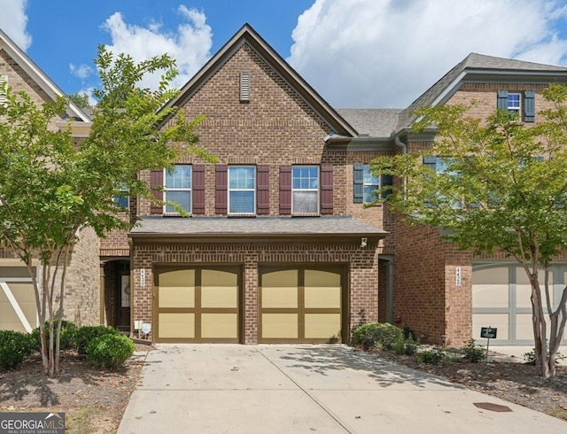 multi unit property with an attached garage, driveway, and brick siding