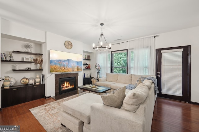 living room with dark wood finished floors, an inviting chandelier, and a glass covered fireplace