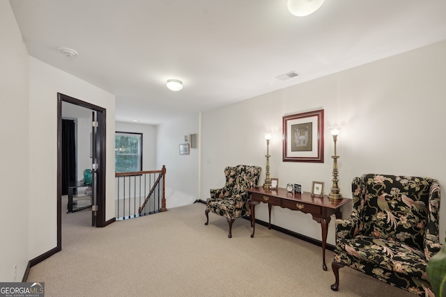 sitting room with baseboards, visible vents, carpet floors, and an upstairs landing