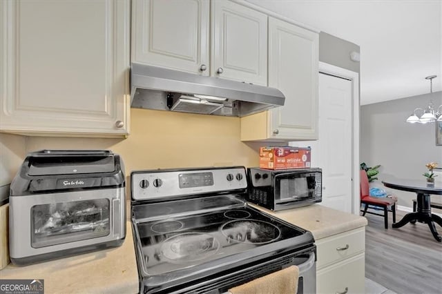 992 Old Holcomb Bridge Rd, Roswell, GA 30076 - kitchen with white cabinets, under cabinet range hood, light countertops, stainless steel range with electric stovetop, and a notable chandelier