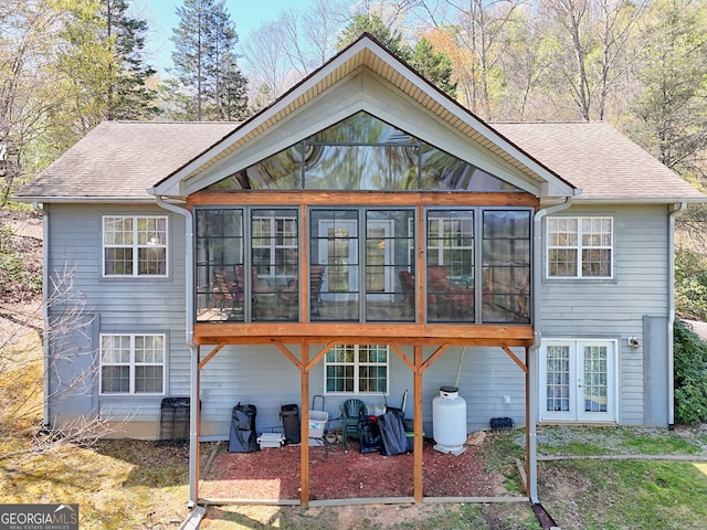 rear view of property featuring roof with shingles, french doors, and a sunroom
