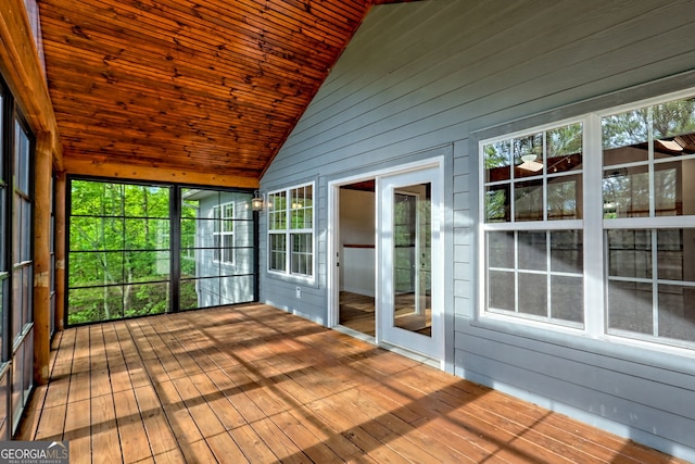 unfurnished sunroom with wood walls, a wooden deck, a wealth of natural light, and hardwood / wood-style flooring
