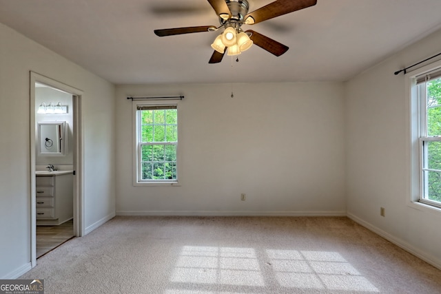unfurnished bedroom with a ceiling fan, a sink, baseboards, carpet flooring, and ensuite bath