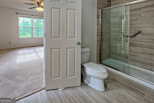 full bath featuring baseboards, a ceiling fan, a shower stall, and toilet